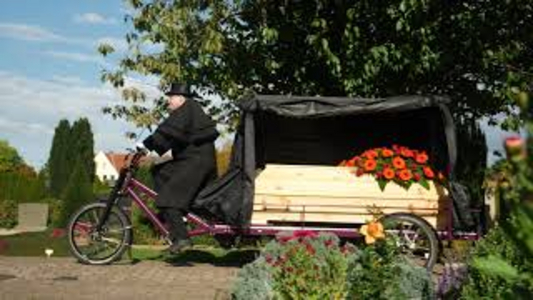 Bestatter Bernd Vogel mit der Bestattungs-Radkutsche fahrend